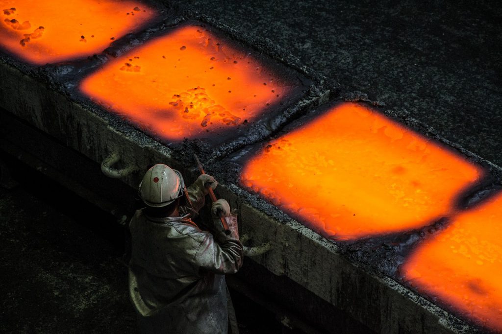 Man in front of glowing hot metallurgy trays for Elmelin, mica specialists
